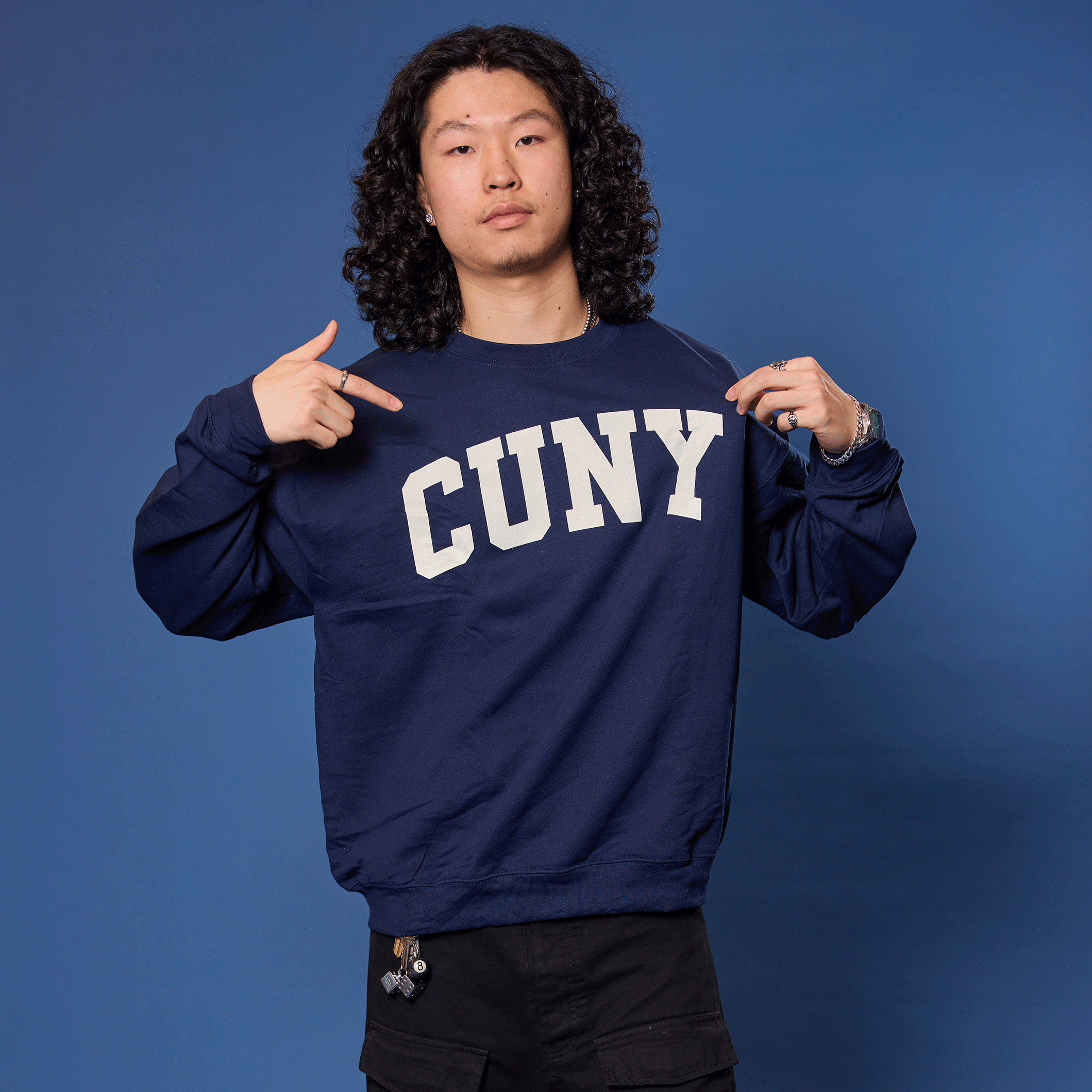 Person wearing a navy blue sweatshirt with 'CUNY' text against a blue background