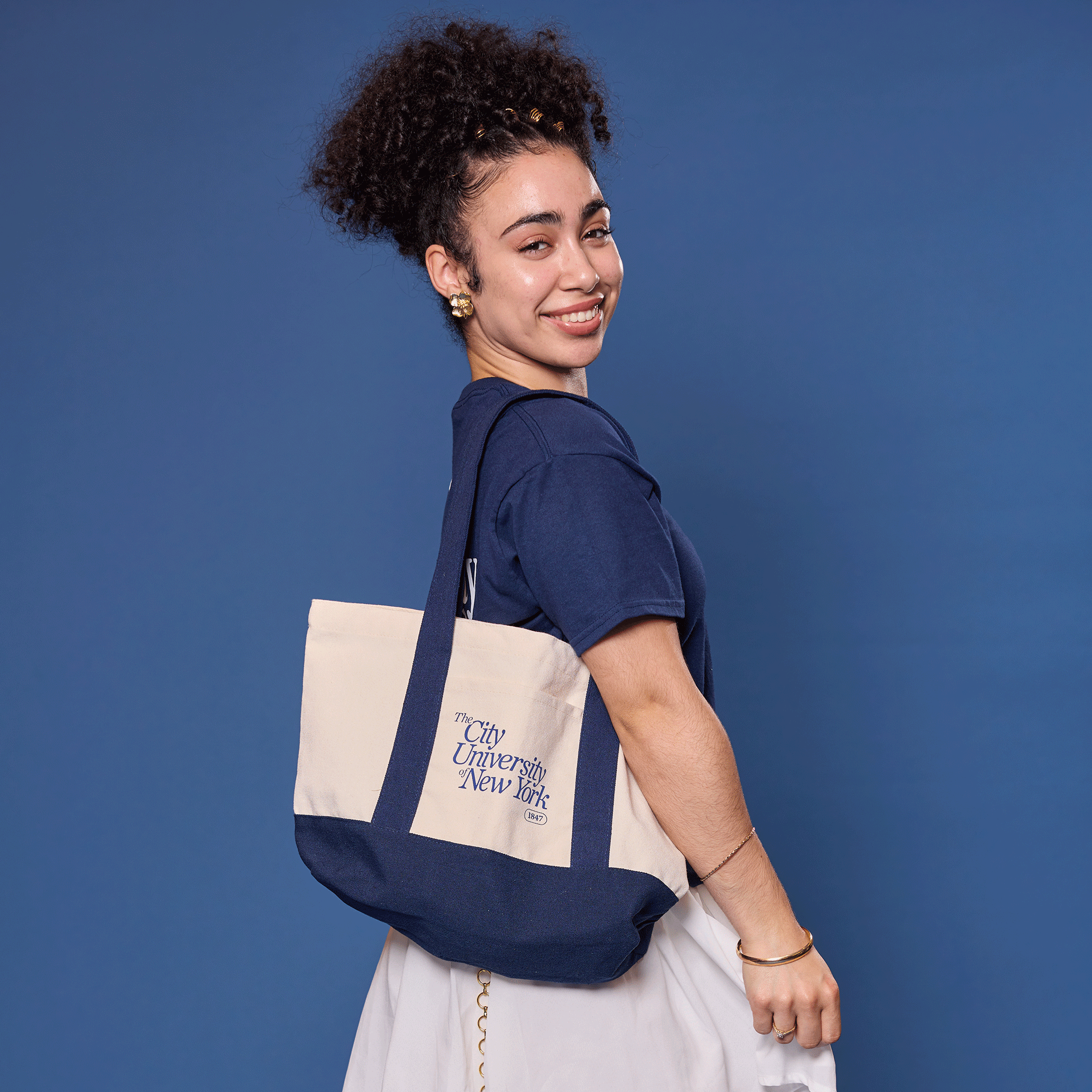 Person wearing a navy tote bag on a blue background